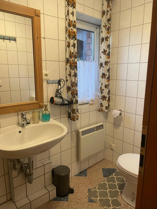 Gefliestes Badezimmer mit Waschbecken, Spiegel und Fenster