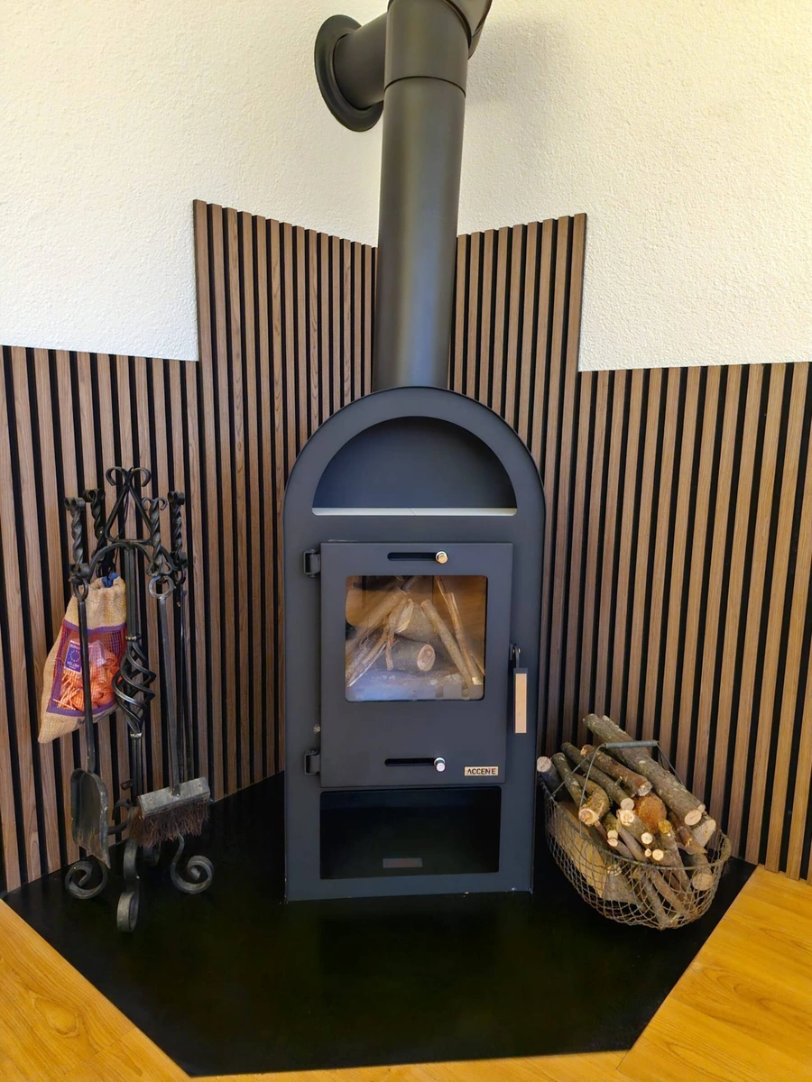 Kaminofen mit Holzvorrat vor einer Wand mit Holzleisten