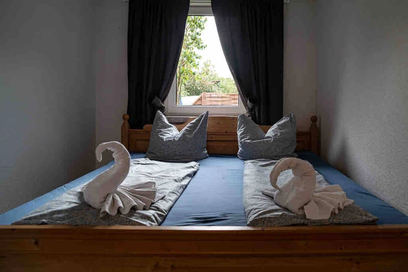 Doppelbett mit blauer Bettwäsche und zu Schwänen gefalteten Handtüchern